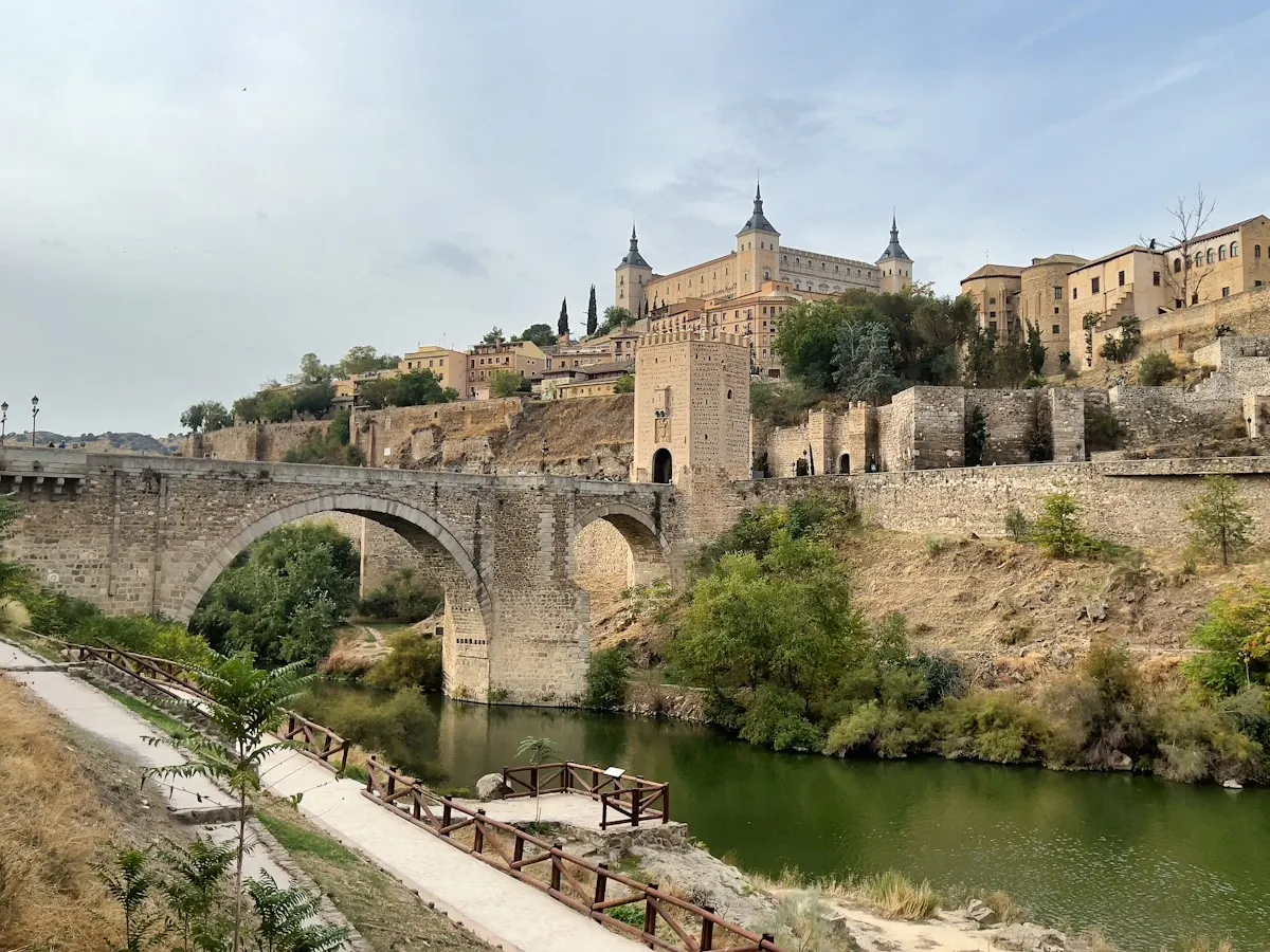 A stone bridge over a river below a castle