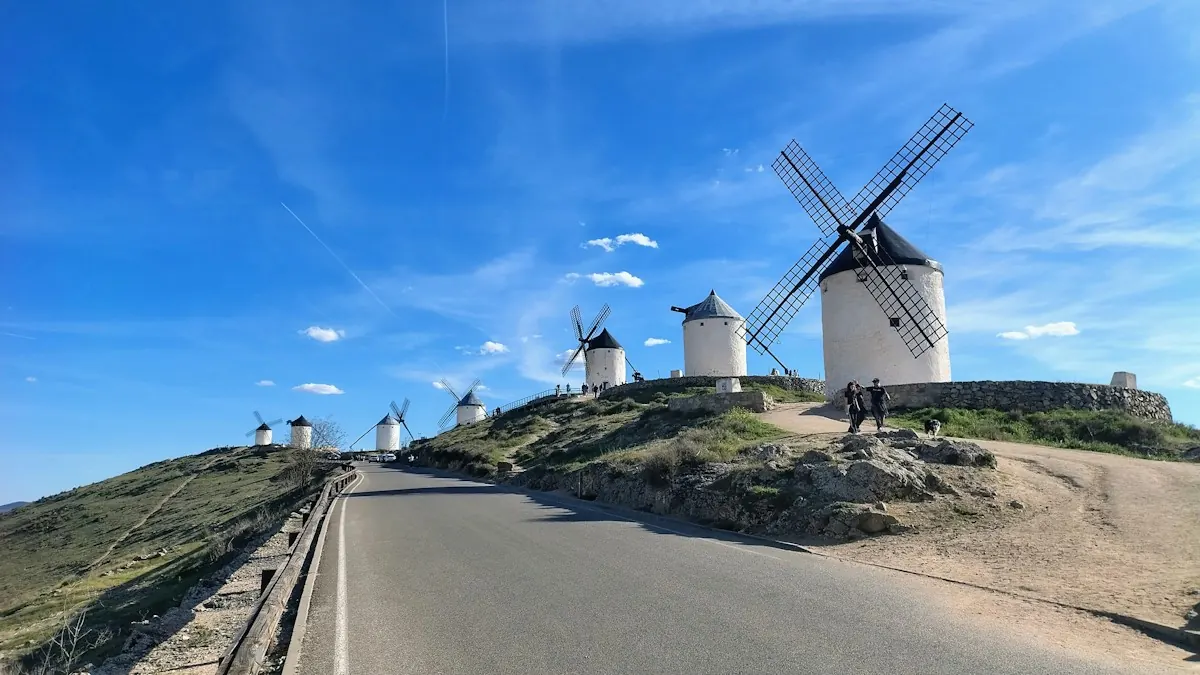White windmills on a rocky hill above a road